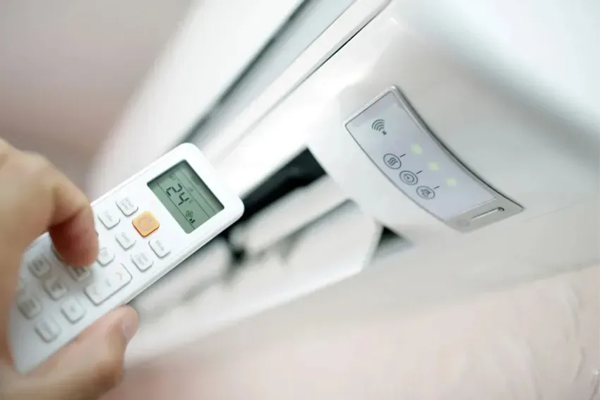 uma pessoa com controle remoto ligando o ar condicionado