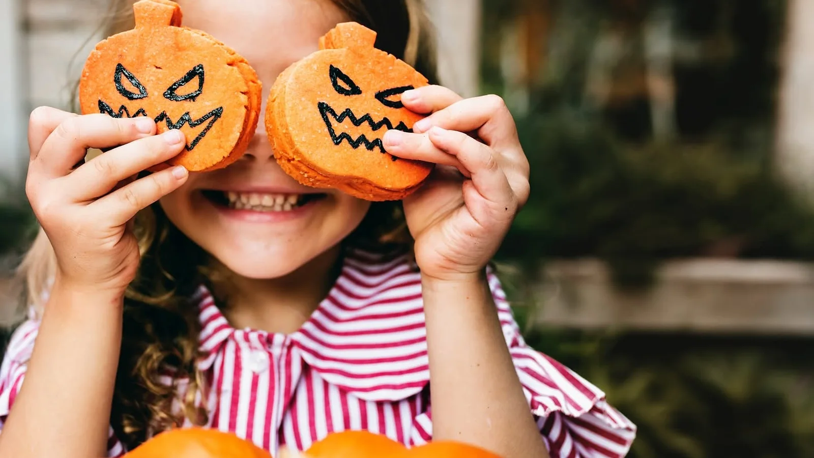 Child holding pumpkin-shaped Halloween treats