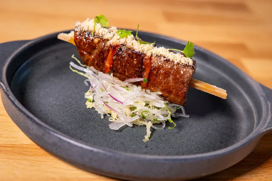 spetinho gourmet servido em prato preto, acompanhado de salada de legumes finamente fatiados, em festival gastronômico em Orlando 2025