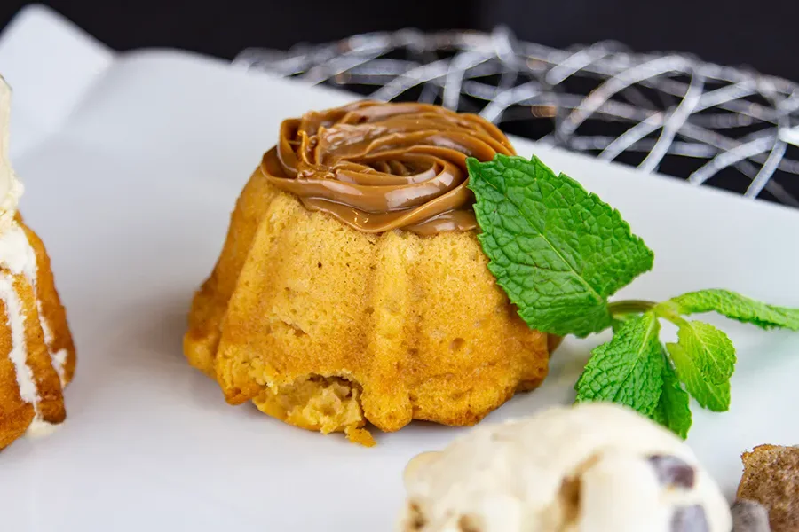 Mini bolo dourado coberto com doce de leite e decorado com folha de hortelã, servido em prato branco durante festival gastronômico em Orlando 2025