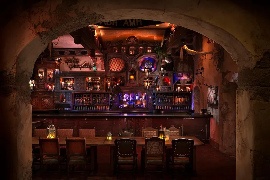 Bar em formato de caveira no The Beak and Barrel da Disney, repleto de garrafas raras, destroços de navio e o papagaio Rummy observando os visitantes.