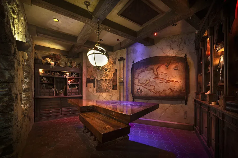 Sala do Cartográfico no The Beak and Barrel, com mesa central repleta de mapas, pergaminhos e instrumentos de navegação.