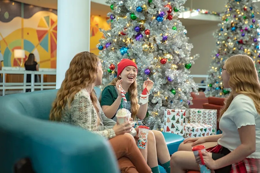 Jovens sentadas no hall do hotel em frente à árvore de Natal 