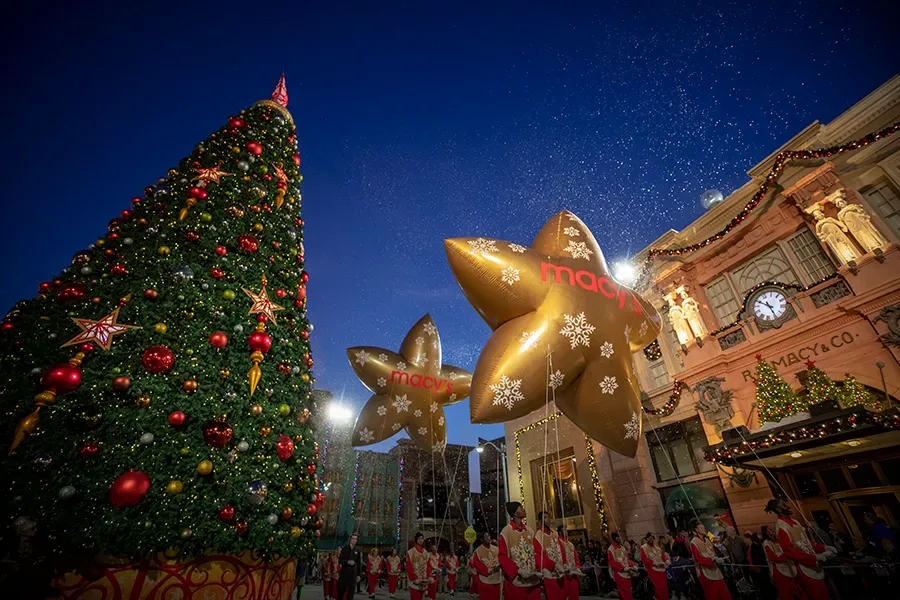 Desfile noturno da Macy's Parade na Universal Orlando ao lado de uma árvore de Natal
