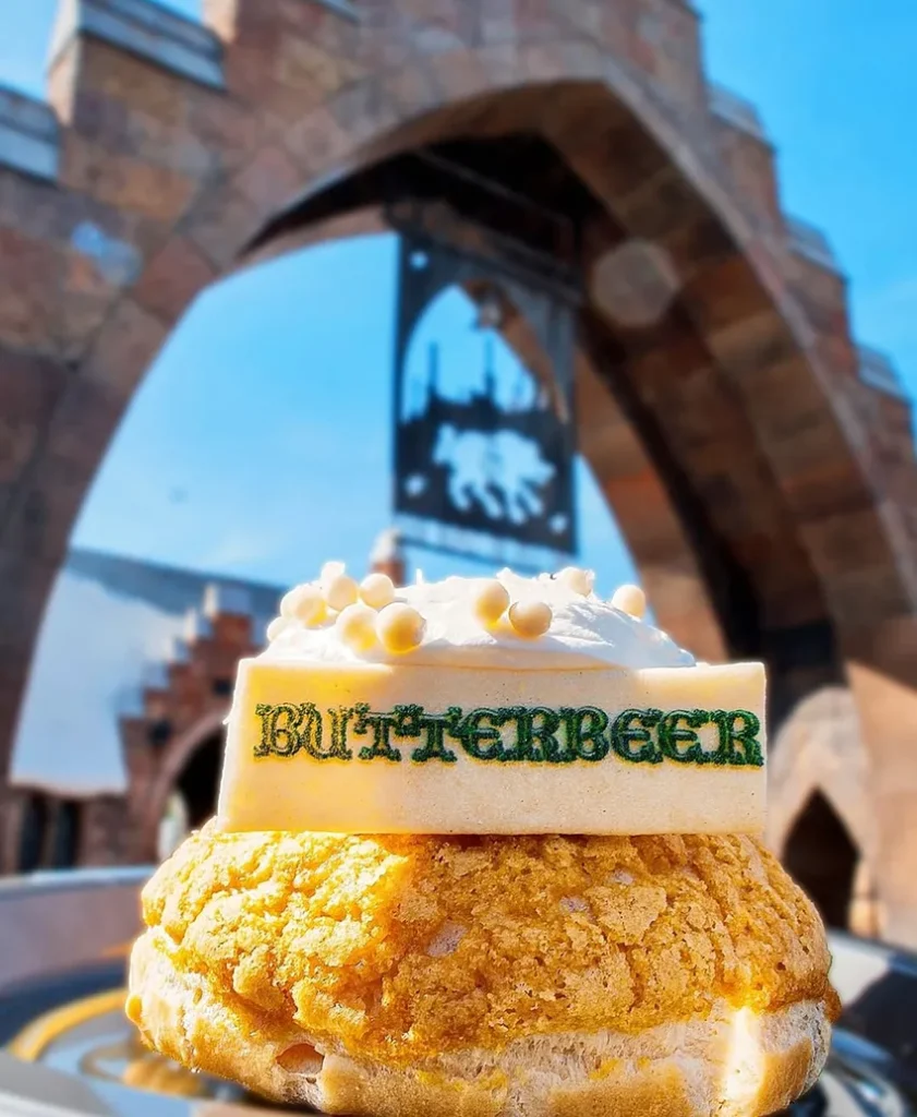 Bolinho feito com cerveja amanteigada em frente ao portal de Hogsmeade no parque Island of Adventure, da Universal Orlando