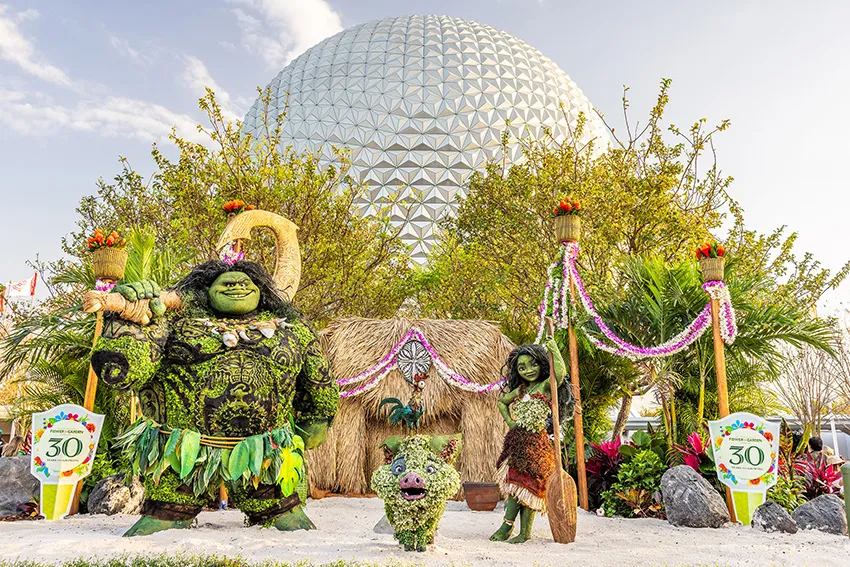 Personagens do filme Moana em forma de topiárias com a bola do Epcot ao fundo
