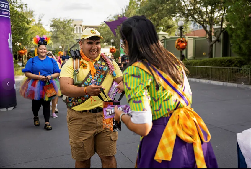 Rapaz com uma sacola pega doces com cast member da Disney durante a festa de Halloween Mickeys-Not-So-Scary Halloween Party 