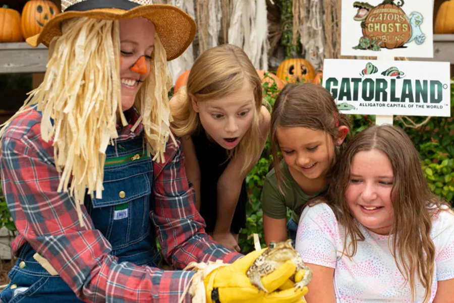 Crianças observam um sapo nas mãos de um espantalho em evento de halloween do Gatorland de Orlando