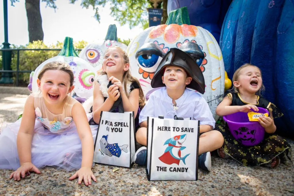 Crianças sentadas com sacolas para coleta de doces na festa de halloween do SeaWorld Orlando