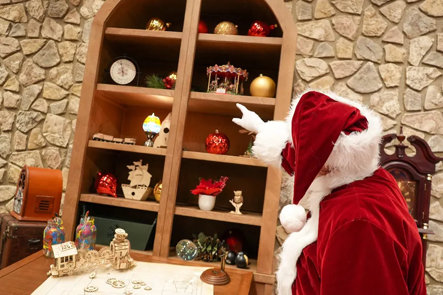 Papai Noel aponta para uma prateleira com artigos natalinos na Disney