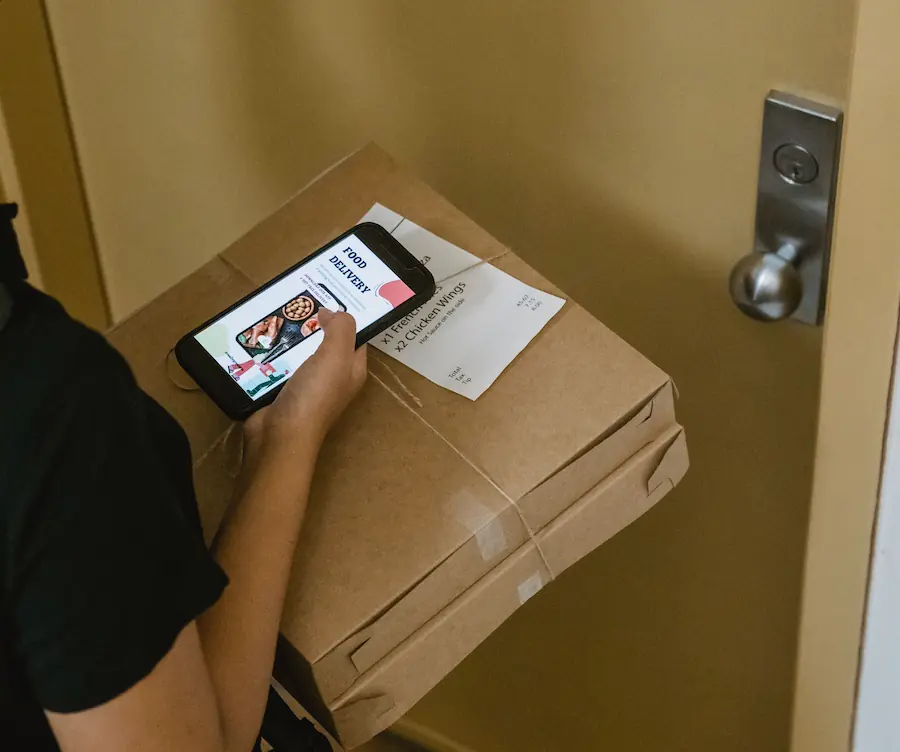 Entregador de pizza bate no quarto de um hotel com um celular nas mãos